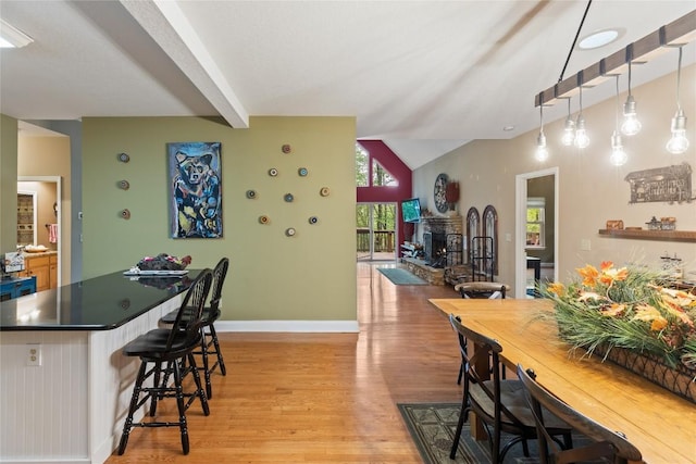 151 Rhododendron Ct, Sapphire, NC 28774 - kitchen with light wood-style floors, a kitchen bar, a center island, a fireplace with raised hearth, and dark countertops