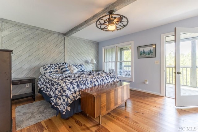 bedroom featuring beam ceiling, wooden walls, and light hardwood / wood-style floors