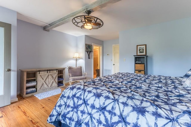 bedroom with beamed ceiling and hardwood / wood-style flooring