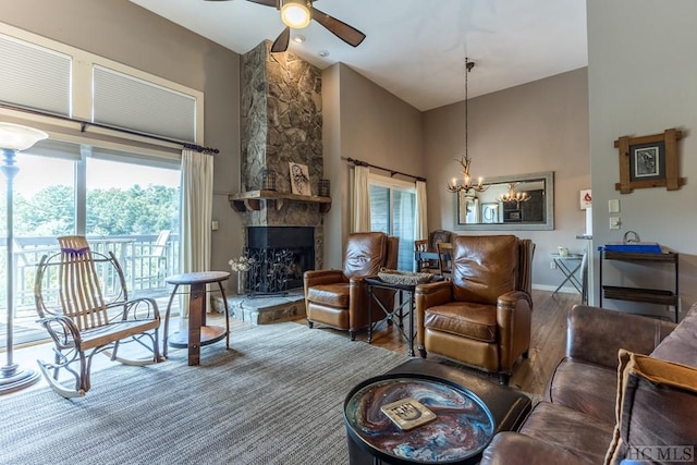 living room featuring hardwood / wood-style flooring, high vaulted ceiling, ceiling fan with notable chandelier, and a fireplace