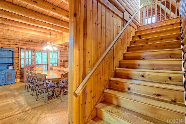 staircase featuring hardwood / wood-style floors, log walls, ceiling fan, wooden ceiling, and beam ceiling