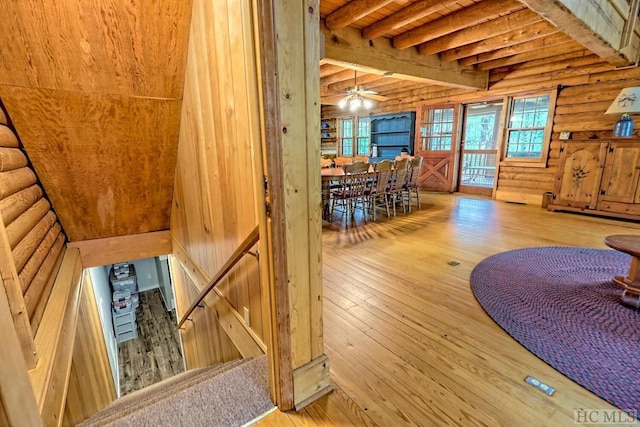 living room featuring beamed ceiling, log walls, wooden ceiling, hardwood / wood-style flooring, and ceiling fan