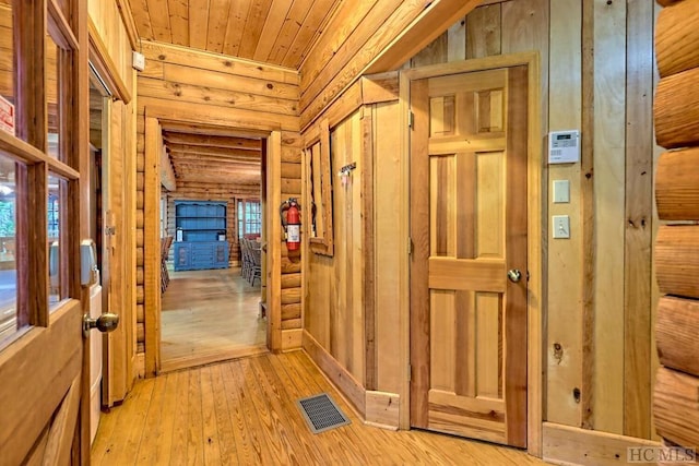 corridor featuring wooden ceiling, light hardwood / wood-style floors, and rustic walls