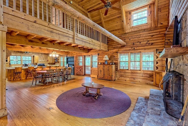 living room with ceiling fan, log walls, wooden ceiling, high vaulted ceiling, and light hardwood / wood-style floors