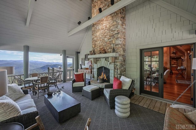 living room with beam ceiling, a mountain view, high vaulted ceiling, and an outdoor stone fireplace