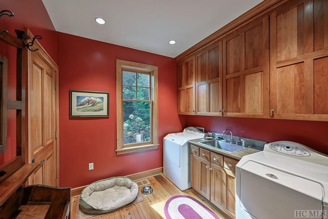 washroom featuring cabinets, sink, washing machine and clothes dryer, and light wood-type flooring