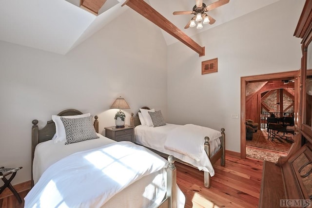 bedroom with lofted ceiling with beams, ceiling fan, and light wood-type flooring