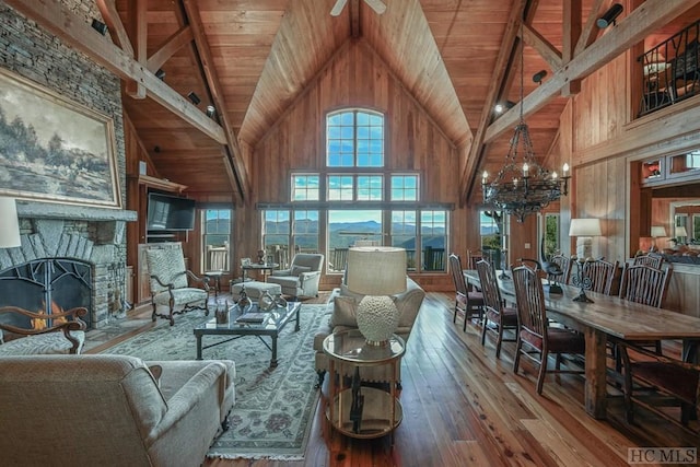 living room with a stone fireplace, hardwood / wood-style floors, high vaulted ceiling, and wood walls