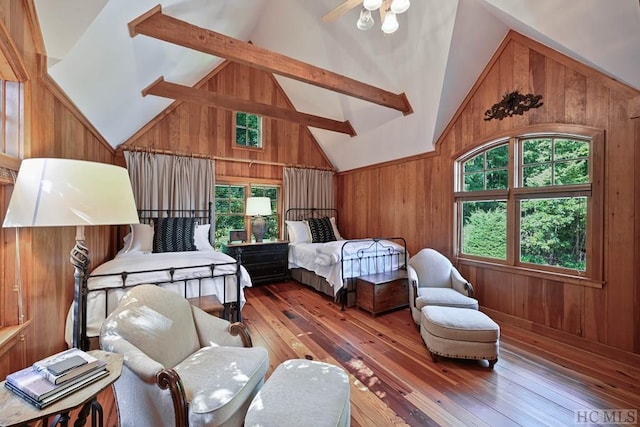 bedroom featuring wood-type flooring, beam ceiling, high vaulted ceiling, and wood walls