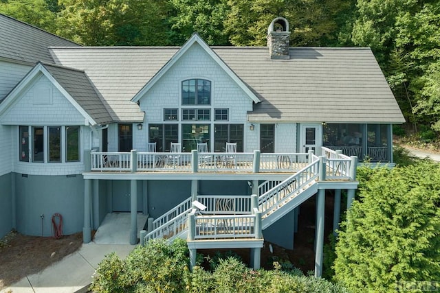 rear view of property featuring a sunroom and a deck