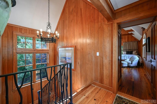 hallway featuring hardwood / wood-style flooring, vaulted ceiling, and wood walls