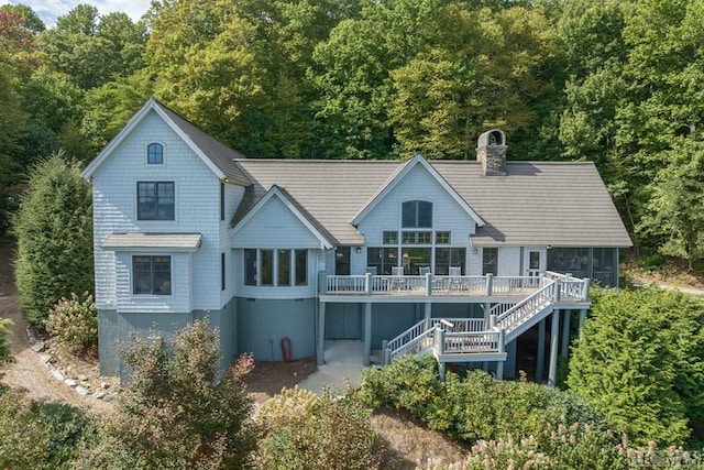 rear view of property featuring a sunroom and a deck