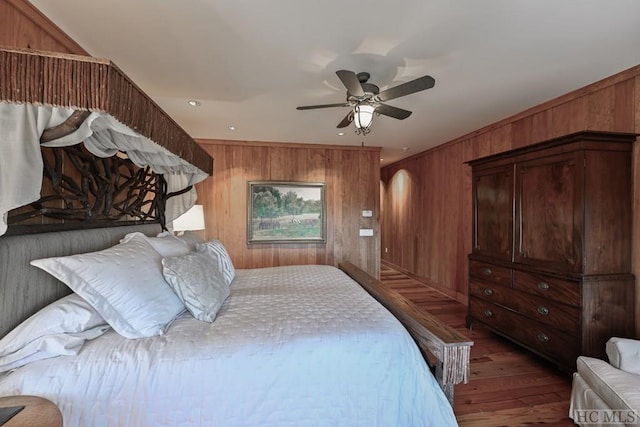 bedroom featuring ceiling fan, dark hardwood / wood-style floors, and wood walls