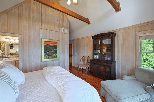 bedroom with connected bathroom, high vaulted ceiling, beamed ceiling, and wood walls