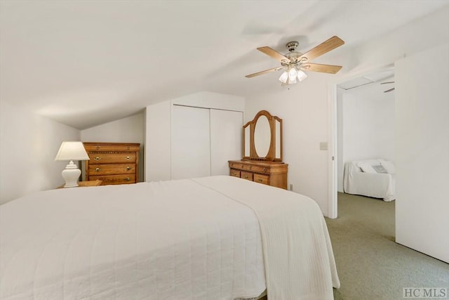 carpeted bedroom with a closet, vaulted ceiling, and ceiling fan