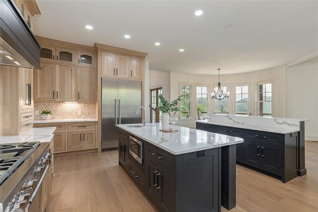 343 Ledgeview Rd, Cashiers, NC 28717 - kitchen featuring a kitchen island with sink, ventilation hood, built in appliances, light wood-type flooring, and a chandelier