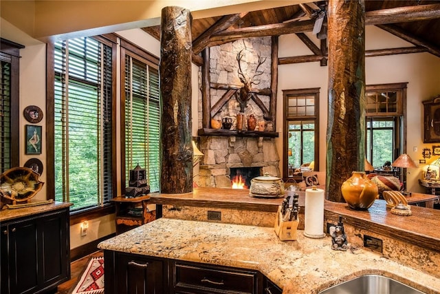 1090 Zeb Alley Rd, Cashiers, NC 28717 - kitchen with light stone countertops, wood finished floors, a stone fireplace, dark cabinetry, and wooden ceiling