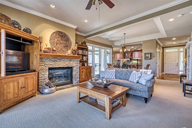 living room with ornamental molding, carpet flooring, recessed lighting, ceiling fan with notable chandelier, and a stone fireplace