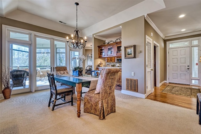 dining space with a chandelier, visible vents, crown molding, and baseboards