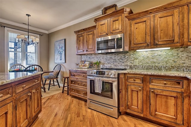 kitchen featuring brown cabinets, appliances with stainless steel finishes, ornamental molding, and an inviting chandelier