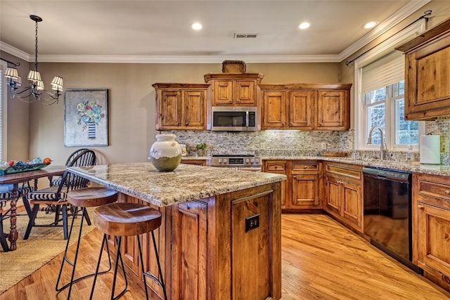 kitchen with brown cabinetry, visible vents, appliances with stainless steel finishes, and a chandelier