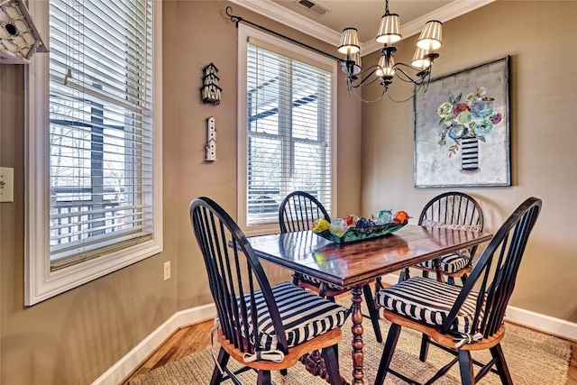 dining space with visible vents, crown molding, baseboards, light wood-style floors, and an inviting chandelier