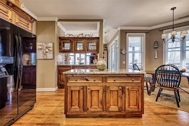 kitchen featuring crown molding, brown cabinetry, black fridge with ice dispenser, and light wood finished floors