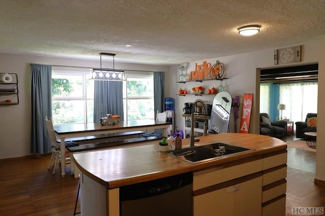 kitchen featuring sink, pendant lighting, dishwasher, dark hardwood / wood-style floors, and a kitchen island with sink