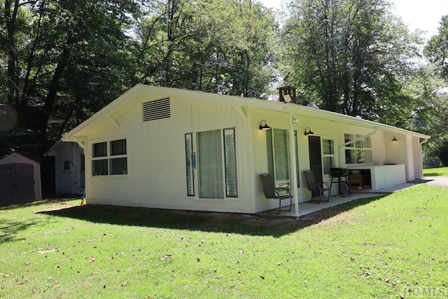 rear view of house featuring a storage shed, a lawn, and a patio area