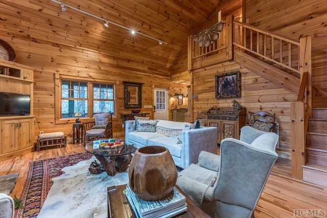 living room with track lighting, wooden walls, and light hardwood / wood-style floors