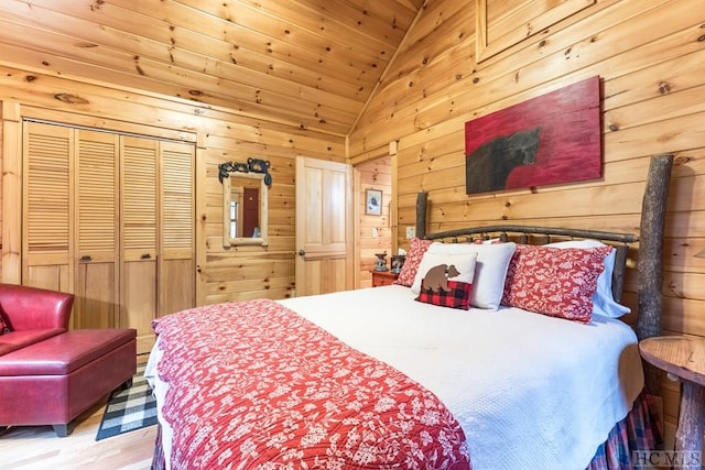 bedroom with vaulted ceiling, wood ceiling, wooden walls, and a closet