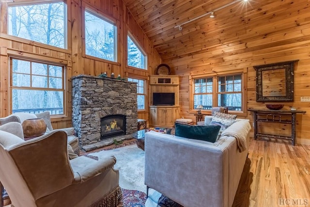 living room featuring a fireplace, high vaulted ceiling, wooden walls, wooden ceiling, and light hardwood / wood-style flooring