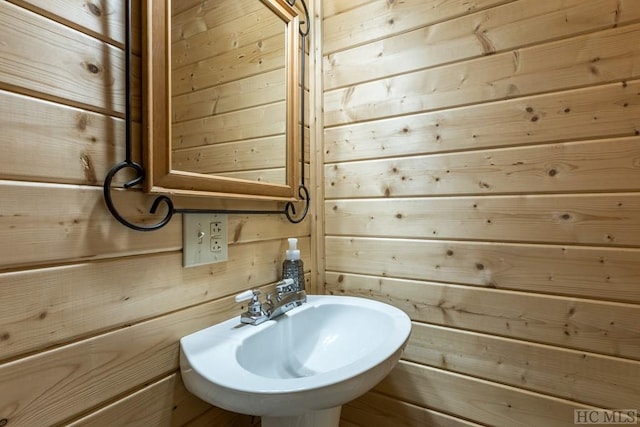 bathroom featuring sink and wooden walls