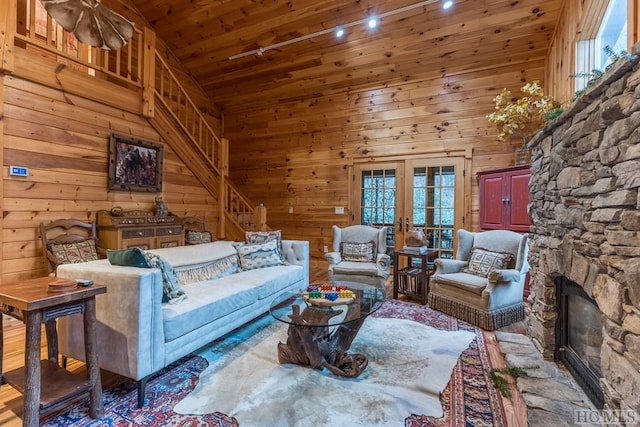 living room with wood walls, a stone fireplace, high vaulted ceiling, and wooden ceiling