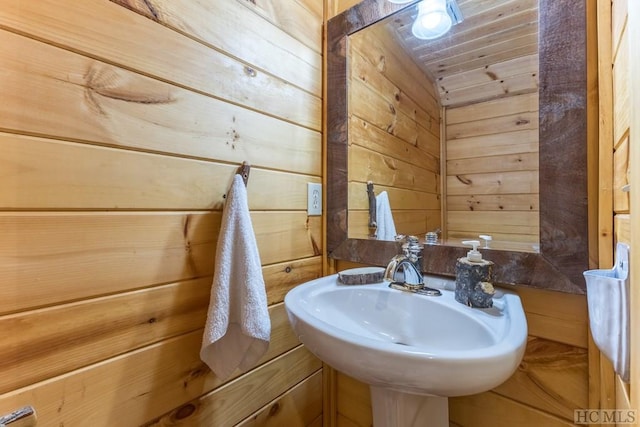 bathroom featuring sink, wooden ceiling, and wooden walls