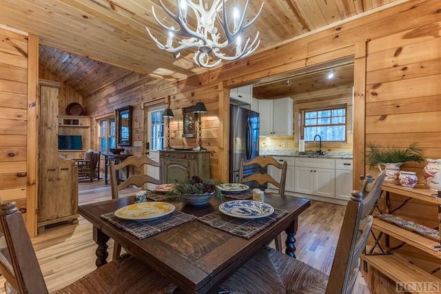 dining space with wooden walls, wooden ceiling, vaulted ceiling, and light wood-type flooring