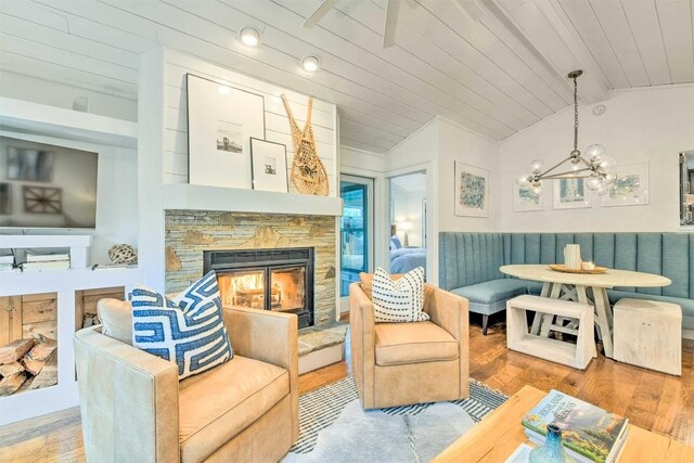 living area featuring a fireplace, a notable chandelier, wood finished floors, breakfast area, and vaulted ceiling with beams