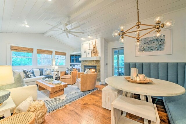 living area with lofted ceiling with beams, a healthy amount of sunlight, ceiling fan with notable chandelier, and light wood-type flooring