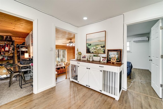 corridor with light hardwood / wood-style flooring and a wall unit AC