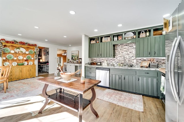 kitchen featuring tasteful backsplash, sink, green cabinets, light hardwood / wood-style floors, and stainless steel appliances