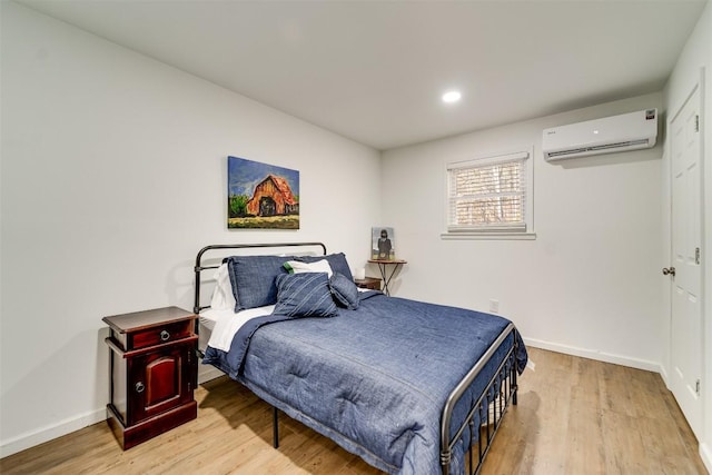 bedroom featuring a wall mounted AC and light wood-type flooring