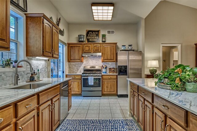 236 Hemlock Woods Dr, Highlands, NC 28741 - kitchen with stainless steel appliances, under cabinet range hood, backsplash, light stone counters, and brown cabinets