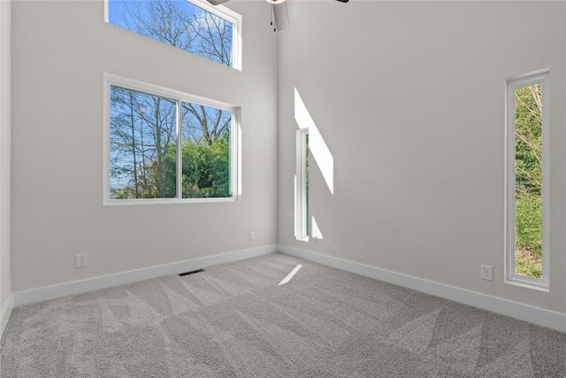 spare room featuring a ceiling fan, carpet, and baseboards