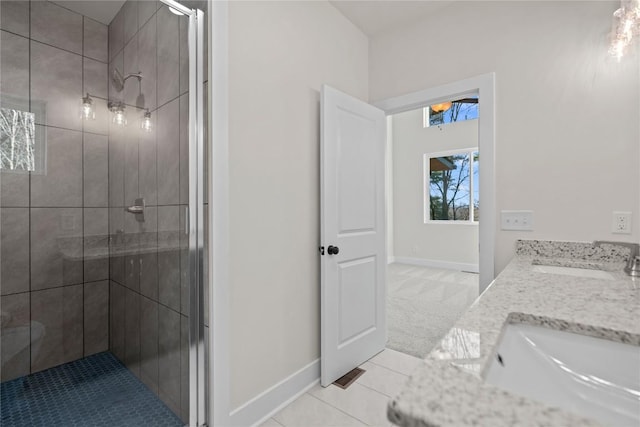 bathroom with a sink, a shower stall, baseboards, and tile patterned flooring