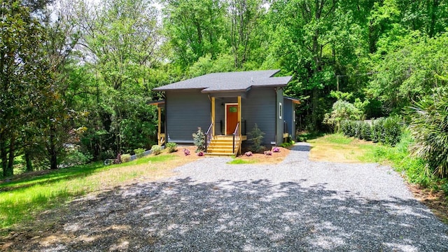 view of front of house featuring gravel driveway and a wooded view