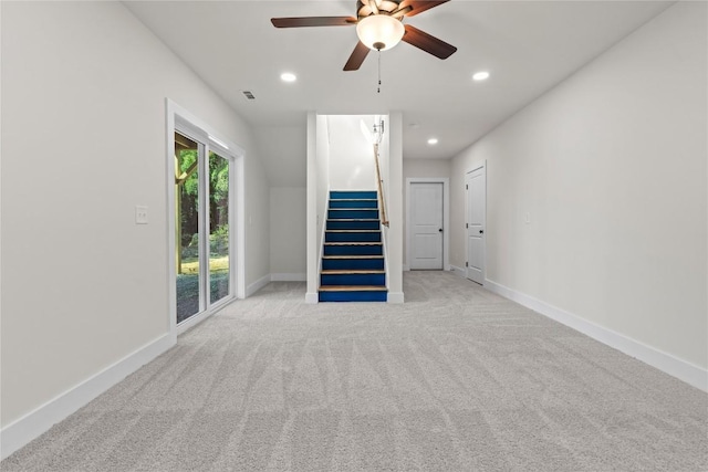 unfurnished living room featuring a ceiling fan, stairs, light colored carpet, recessed lighting, and baseboards