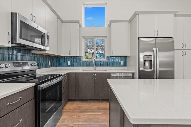 kitchen featuring stainless steel appliances, a sink, light countertops, and white cabinetry