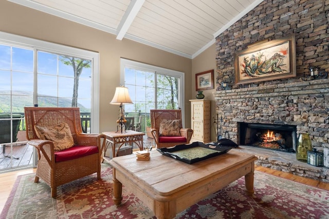 sitting room featuring wood finished floors, a stone fireplace, crown molding, and wood ceiling