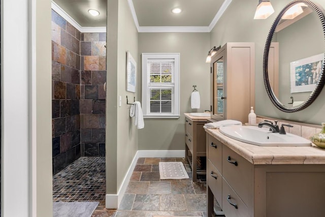 full bath with stone tile flooring, a walk in shower, ornamental molding, baseboards, and two vanities