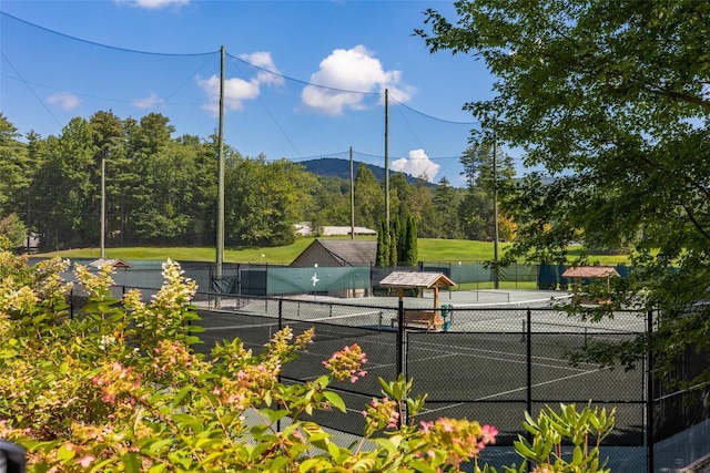 view of tennis court featuring fence and a mountain view
